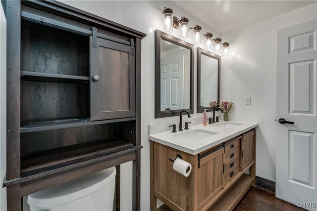 36852 Middle Rd, Orleans, NY 13656 - bathroom featuring toilet, wood finished floors, double vanity, and baseboards