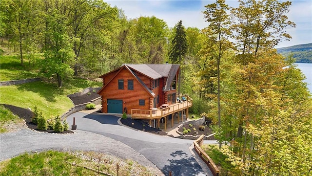 1267 S Lake Rd, Middlesex, NY 14507 - view of front of house with asphalt driveway, an attached garage, log exterior, a forest view, and a deck