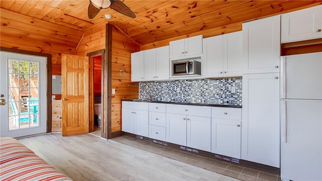1267 S Lake Rd, Middlesex, NY 14507 - kitchen with freestanding refrigerator, lofted ceiling, stainless steel microwave, wood ceiling, and tasteful backsplash