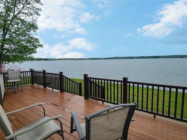 wooden terrace featuring a water view and a lawn