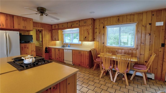 kitchen featuring white appliances, light countertops, wooden walls, a sink, and a ceiling fan