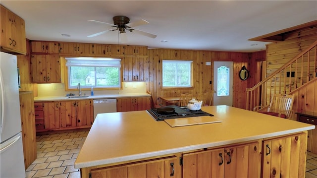 kitchen featuring white appliances, a sink, light countertops, ceiling fan, and a kitchen island