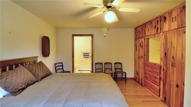 bedroom featuring a baseboard heating unit, light wood-type flooring, ensuite bath, baseboards, and ceiling fan