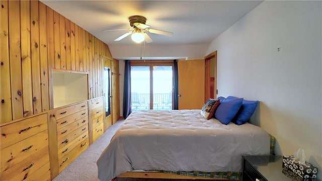 bedroom with carpet flooring, wood walls, access to outside, and a ceiling fan
