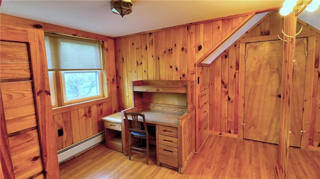 office with a baseboard heating unit, light wood-style floors, and wooden walls