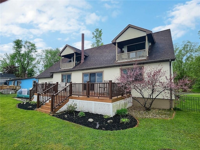 rear view of property with a balcony, roof with shingles, and stucco siding