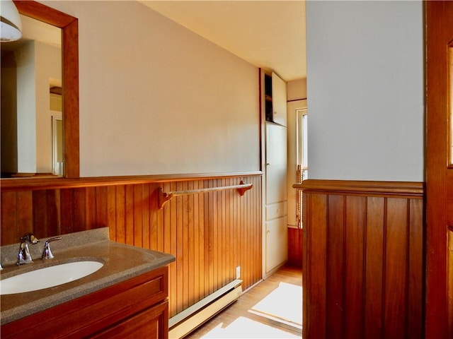 7 Walnut St, Oneonta-City, NY 13820 - bathroom with baseboard heating, wainscoting, wooden walls, vanity, and wood finished floors