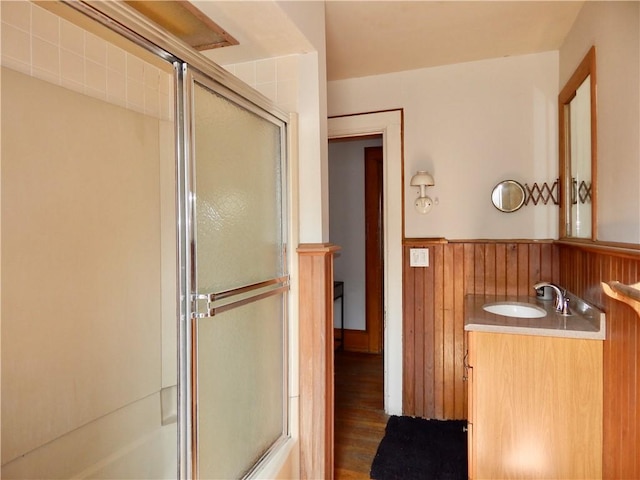 7 Walnut St, Oneonta-City, NY 13820 - full bathroom with vanity, a wainscoted wall, wood finished floors, wood walls, and bath / shower combo with glass door