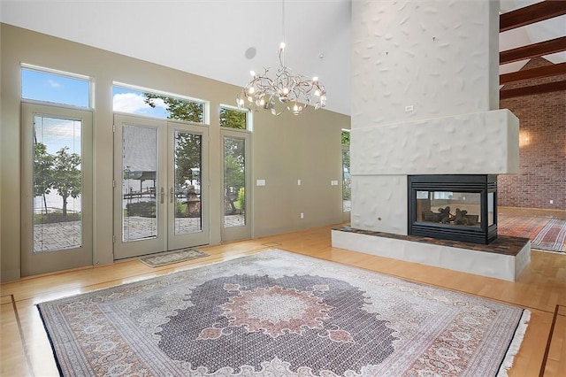 4331 Tichenor Point Dr, Canandaigua-Town, NY 14424 - unfurnished living room with a chandelier, a high ceiling, a tile fireplace, wood finished floors, and french doors