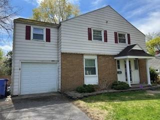 view of front of home with an attached garage, asphalt driveway, and a front yard