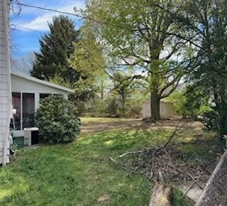 view of green lawn with central air condition unit and a sunroom