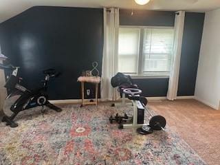 exercise area featuring carpet flooring, lofted ceiling, and baseboards