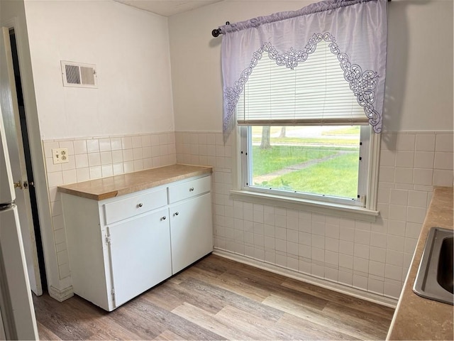 167 Rogers Pkwy, Irondequoit, NY 14617 - kitchen with tile walls, light wood-style flooring, white cabinetry, wainscoting, and light countertops