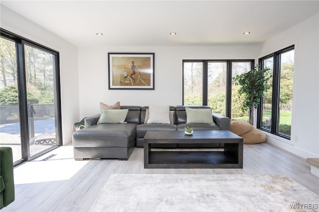 living area with healthy amount of natural light, wood finished floors, recessed lighting, and baseboards