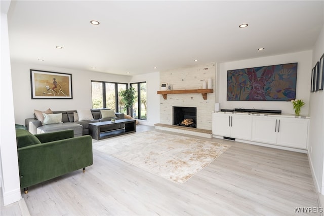 living room with recessed lighting, a fireplace, and light wood-type flooring