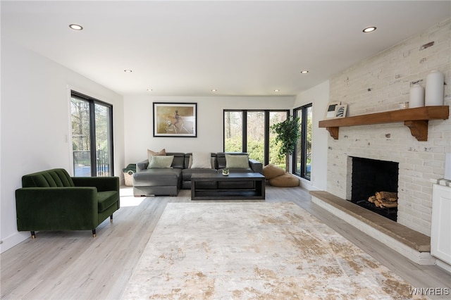 living area featuring light wood-style floors, recessed lighting, a brick fireplace, and baseboards