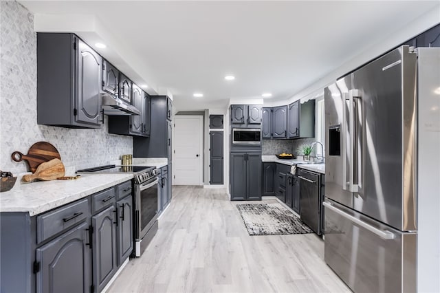 848 Weiland Rd, Greece, NY 14626 - kitchen featuring stainless steel appliances, under cabinet range hood, tasteful backsplash, light wood-type flooring, and light countertops