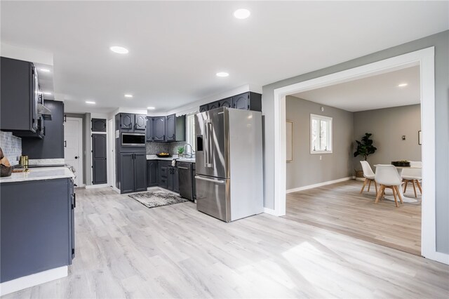 848 Weiland Rd, Greece, NY 14626 - kitchen featuring appliances with stainless steel finishes, light countertops, backsplash, a sink, and light wood-type flooring