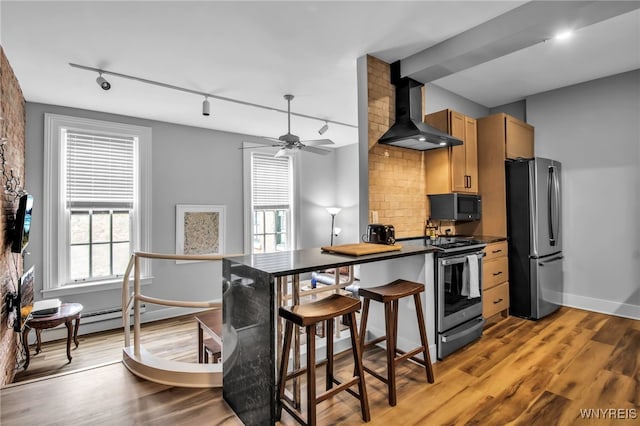 125 Edward St Unit 2G, Buffalo, NY 14201 - kitchen featuring stainless steel appliances, wall chimney range hood, track lighting, decorative backsplash, and plenty of natural light