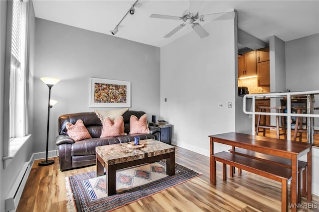 125 Edward St Unit 2G, Buffalo, NY 14201 - living room with a baseboard heating unit, rail lighting, a ceiling fan, light wood-style flooring, and baseboards