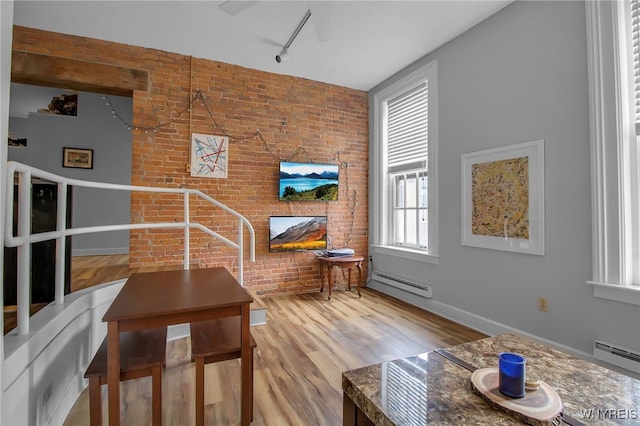 125 Edward St Unit 2G, Buffalo, NY 14201 - living room featuring baseboard heating, rail lighting, brick wall, wood finished floors, and a fireplace