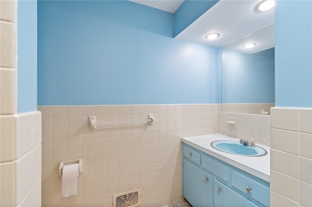 bathroom with tile walls, a wainscoted wall, and vanity
