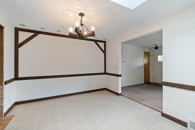 spare room featuring a chandelier and baseboards