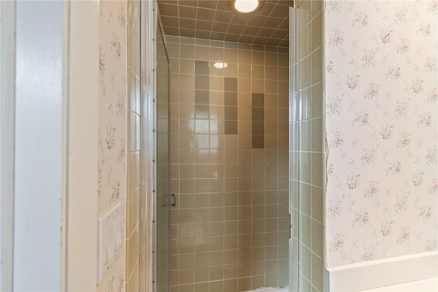 bathroom with wallpapered walls and a stall shower