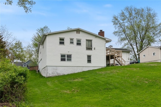 rear view of property featuring stairway, a chimney, a wooden deck, and a lawn