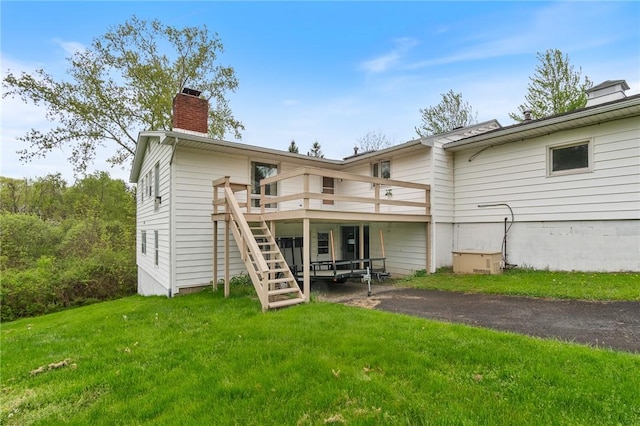 back of property featuring a chimney, stairway, a deck, and a lawn