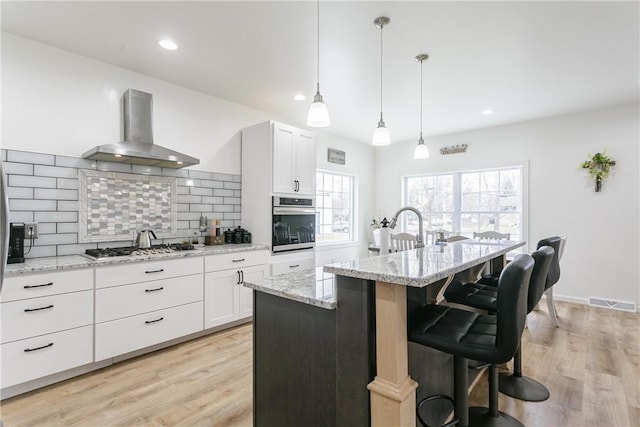 1965 Main St, Carlton, NY 14571 - kitchen featuring wall chimney exhaust hood, stainless steel appliances, tasteful backsplash, light wood-style flooring, and recessed lighting