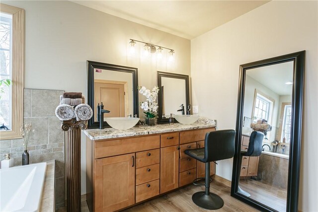 1965 Main St, Carlton, NY 14571 - bathroom featuring wood finished floors, a relaxing tiled tub, and double vanity