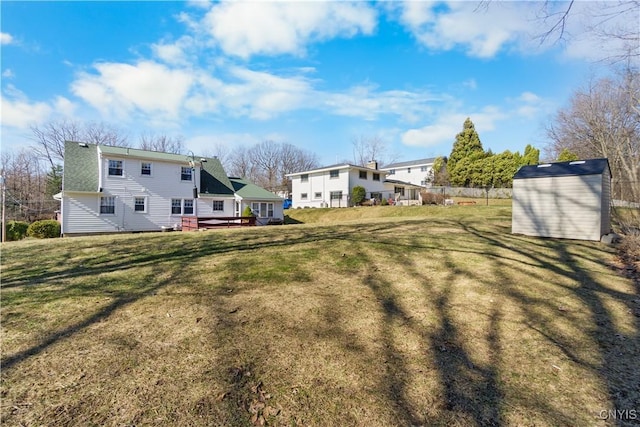 view of grassy yard featuring a shed, an outbuilding, and a deck