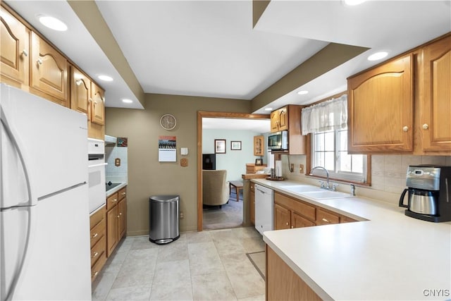kitchen featuring white appliances, a sink, decorative backsplash, recessed lighting, and light countertops
