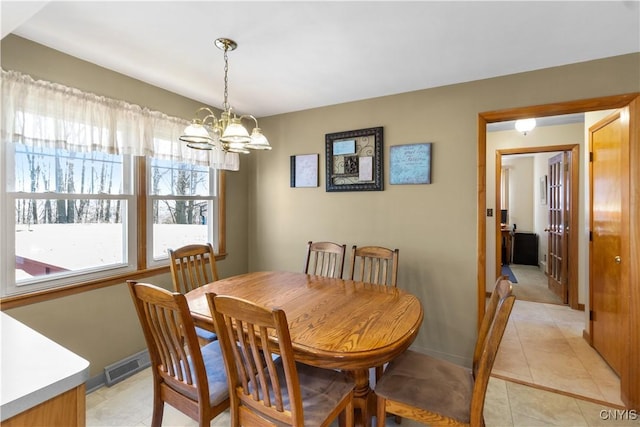 dining area featuring a chandelier, light tile patterned floors, and baseboards