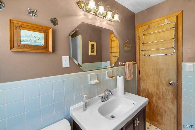 bathroom featuring tile walls, vanity, toilet, and a wainscoted wall