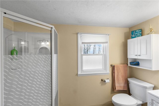 bathroom with a shower stall, toilet, and baseboards