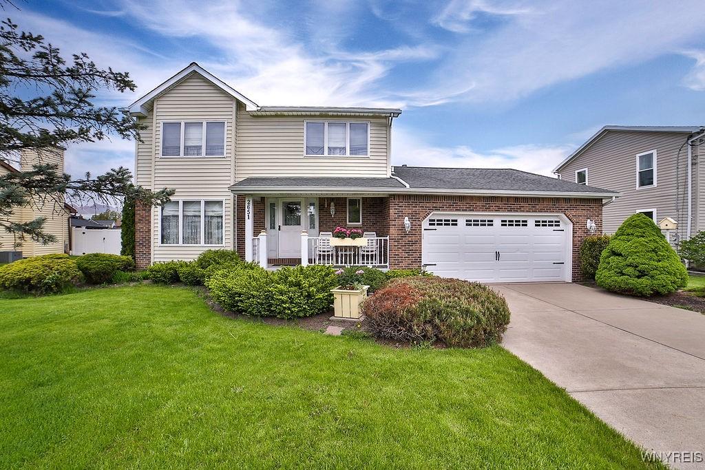2651 Ferchen St, Wheatfield, NY 14304 - traditional home with brick siding, a front yard, an attached garage, and driveway