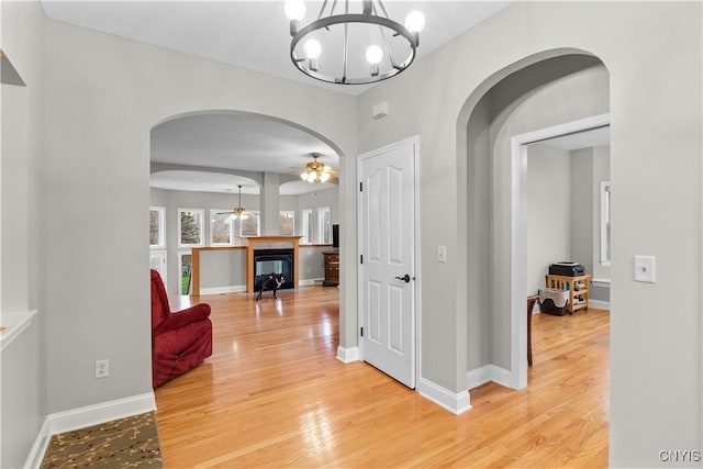 8312 Partridgeberry Dr, Lysander, NY 13027 - hall with arched walkways, a chandelier, light wood-style floors, and baseboards
