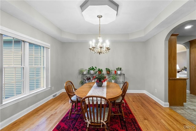 8312 Partridgeberry Dr, Lysander, NY 13027 - dining room with arched walkways, a chandelier, wood finished floors, and a tray ceiling