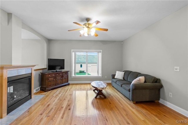 8312 Partridgeberry Dr, Lysander, NY 13027 - living room featuring light wood-style floors, a ceiling fan, baseboards, and a tiled fireplace