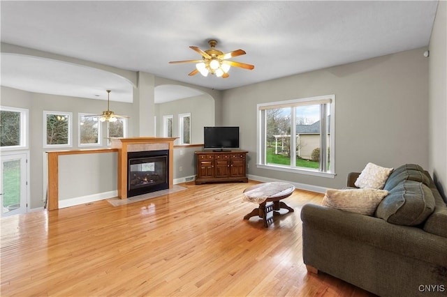 8312 Partridgeberry Dr, Lysander, NY 13027 - living area featuring ceiling fan, light wood finished floors, a fireplace with flush hearth, arched walkways, and baseboards