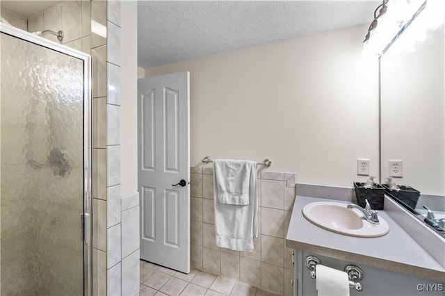 8312 Partridgeberry Dr, Lysander, NY 13027 - bathroom featuring tile patterned floors, a stall shower, tile walls, vanity, and a textured ceiling
