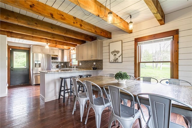 dining room with dark wood-type flooring, beam ceiling, wooden ceiling, and wooden walls