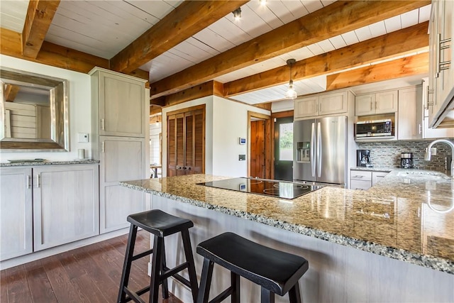 kitchen featuring stainless steel appliances, dark wood finished floors, light stone countertops, a sink, and backsplash