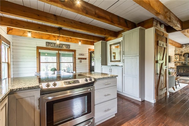 kitchen with stainless steel electric stove, a wood stove, dark wood-style floors, wood walls, and beamed ceiling