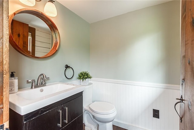 bathroom featuring a wainscoted wall, toilet, and vanity
