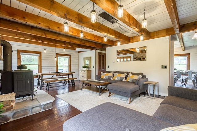 living room with beamed ceiling, wood-type flooring, a wood stove, and baseboards