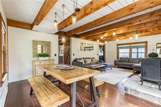 dining room with dark wood finished floors, beamed ceiling, and baseboards