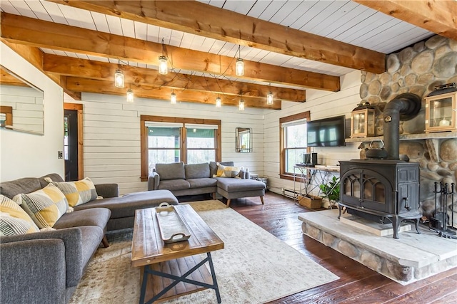 living room featuring dark wood finished floors, a wood stove, wood walls, wooden ceiling, and beam ceiling